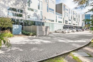 A modern building with a paved entrance, parked cars, and a clear sky. - Landing | Stunning 1BD in University Circle (Cleveland)