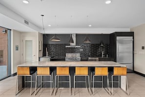 A modern kitchen with a large island, bar stools, a built-in stove, and pendant lighting. - Landing | Stunning Studio in Central West End (St. Louis)