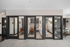 A modern interior with a glass partition, a staircase, and a seating area. - Landing | Incredible 1BD in Central West End (St. Louis)