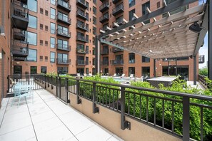 A multi-story residential building with balconies, a rooftop pool area, and a covered outdoor seating area. - Landing | Chic 2BD in Central West End (St. Louis)