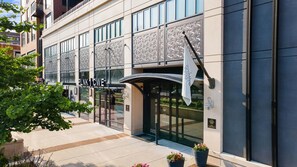 A modern building with a glass facade, a prominent entrance with a curved awning, and a sign that reads 'PLNK CWE'. - Landing | Chic 2BD in Central West End (St. Louis)