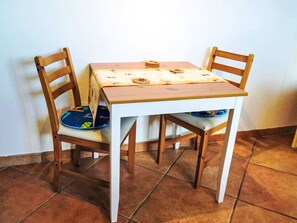 A small dining table with two chairs, a tablecloth, and a plate with a checkered pattern. - Bee Aeschi by Interhome (Aeschi bei Spiez)