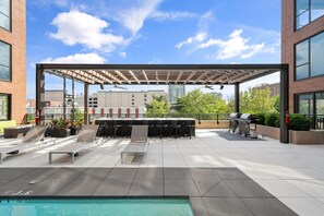 An outdoor patio with a pool, sun loungers, a barbecue area, and a pergola. - Landing | Incredible 2BD in Central West End (St. Louis)