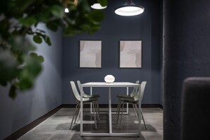 Ein moderner Essbereich mit einem weißen Tisch und Stühlen, zwei gerahmten Kunstwerken an der Wand und einer Pendelleuchte darüber.