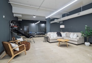 Ein modernes Wohnzimmer mit einer Couch, einem Sessel, einem Couchtisch und einem Tischtennistisch.