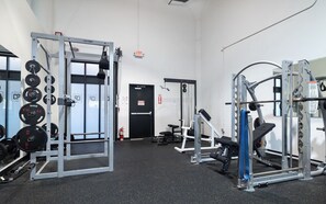 A gym with weightlifting equipment, a door marked 'EXIT', and a fire extinguisher. - Landing | Beautiful 2BD, Yoga Studio (Akron)