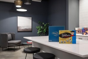 A modern kitchen with a white countertop, two black stools, a grey sofa, and a framed picture on the wall. - Landing | Beautiful 2BD, Yoga Studio (Akron)
