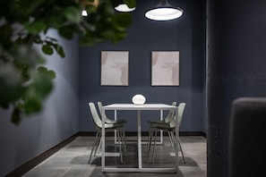 Ein moderner Essbereich mit einem weißen Tisch und Stühlen, zwei gerahmten Kunstwerken an der Wand und einer Pendelleuchte darüber.