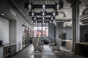 A modern interior with a central staircase, seating area, and industrial-style lighting. - Landing | Spectacular 1BD, Yoga Studio (Akron)