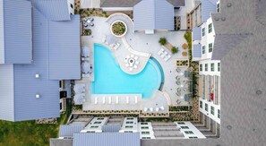 Vue aérienne d’un hôtel doté d’une piscine centrale, de plusieurs espaces de détente et d’une cour aménagée.