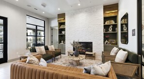 A modern living room with a fireplace, sofas, and a bookshelf. - Landing | Stylish 2BD in Downtown Dripping Springs (Dripping Springs)