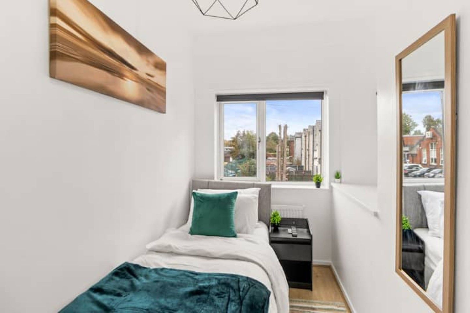 Une chambre à coucher avec un lit, une fenêtre, une table de chevet et un miroir.
