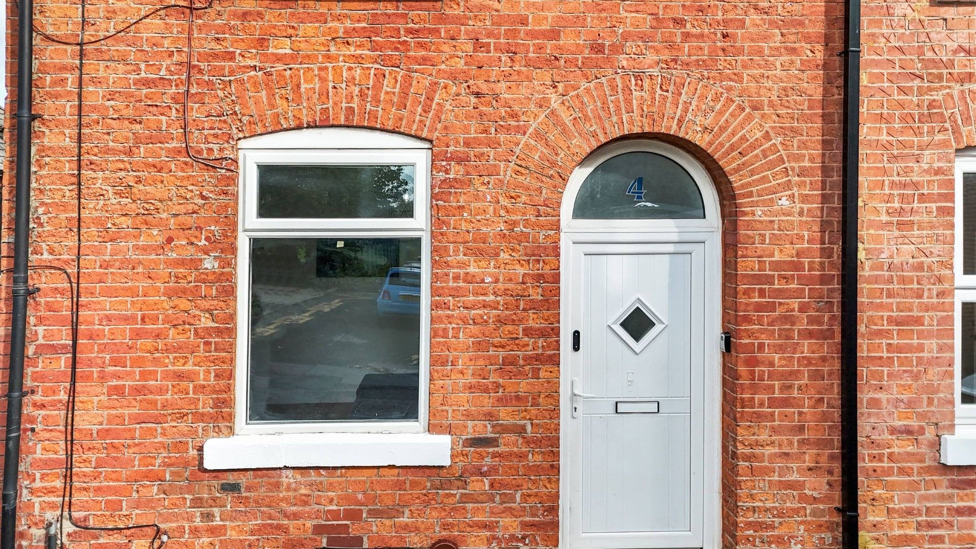 A red brick building with a white door and a window.