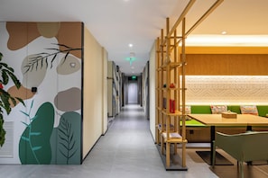 A hallway with a modern design, including a wooden bookshelf and a seating area with a table and chairs. - Jing'an TRUE GO Hotel  (Shanghai)