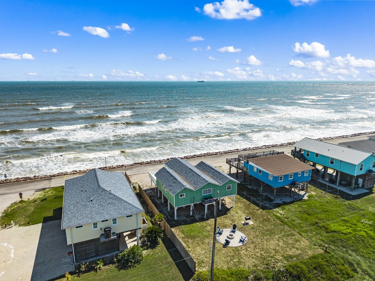 A coastal property with multiple buildings, a beach access, and a view of the ocean.
