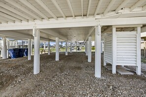 Un espace extérieur abrité, doté d’un sol en gravier, de colonnes blanches et d’un banc en bois.