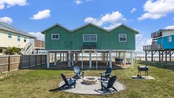 A two-story house with a covered patio area, outdoor seating, and a barbecue grill.