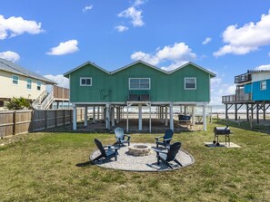 Une maison à deux étages dotée d’un patio couvert, d’un espace salon extérieur et d’un barbecue.