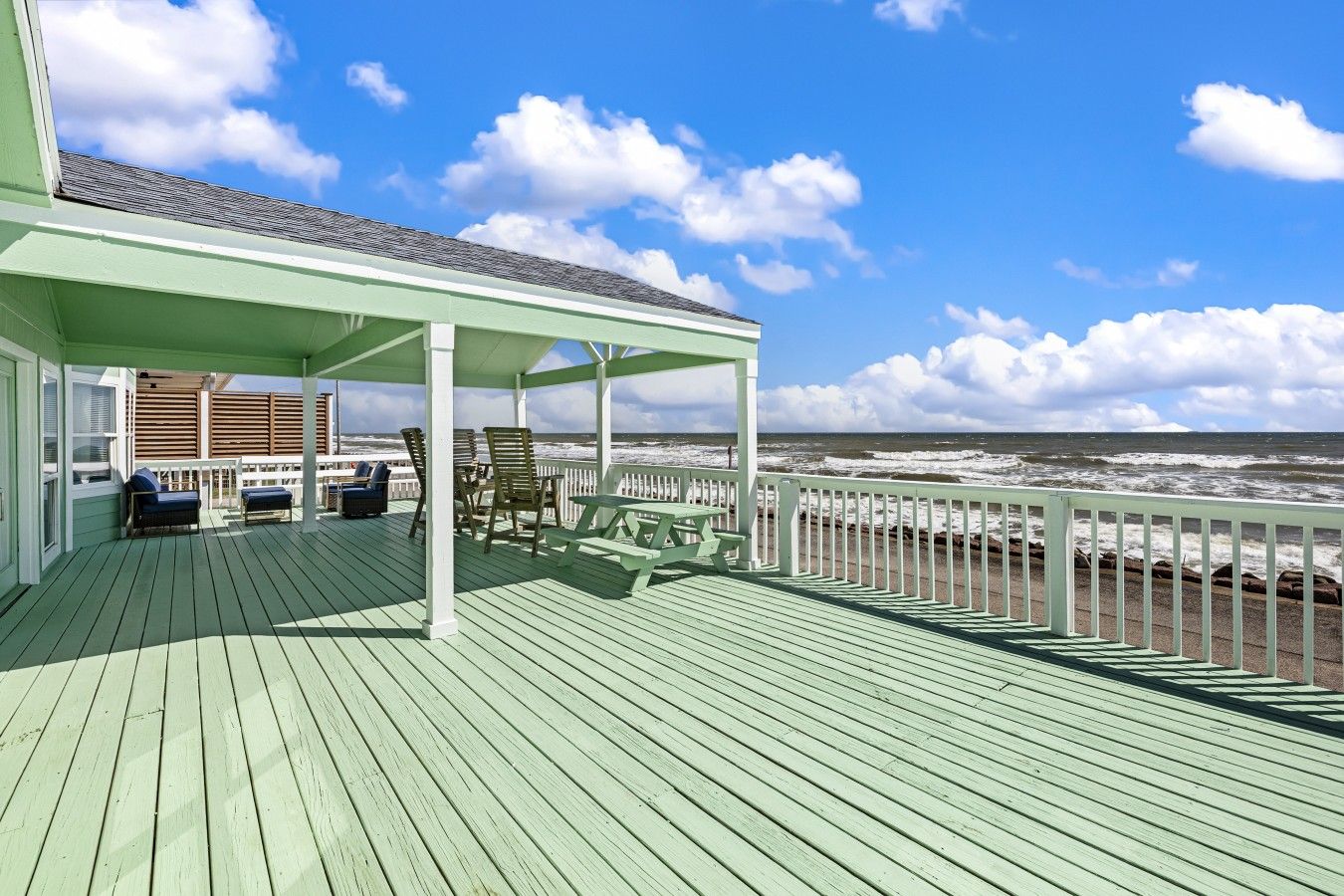 A covered deck with seating and a view of the ocean.