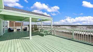 A covered deck with seating and a view of the ocean.