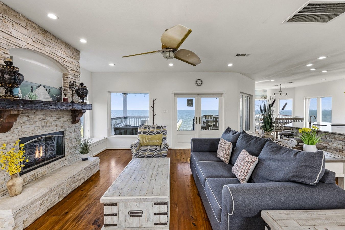 A spacious living room with a fireplace, a sofa set, a coffee table, and a view of the ocean.