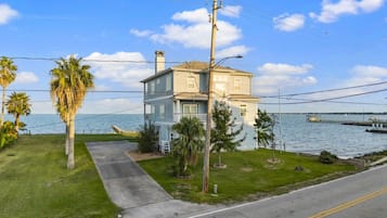 Una casa de dos pisos con un porche delantero y vista al agua.
