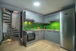 A modern kitchen with grey cabinets, a stainless steel refrigerator, and a green tiled backsplash. - Villa Casa del Miele - Holidays in Crete (Skonízo)
