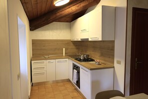 Eine kleine Küche mit weißen Schränken, einer Holz Arbeitsplatte und einem eingebauten Backofen.