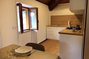 A compact kitchen with a window, a dining table with chairs, and a small countertop with kitchen appliances. - Botton D'oro - One Bedroom Apartment, Sleeps 4 (Teveno)