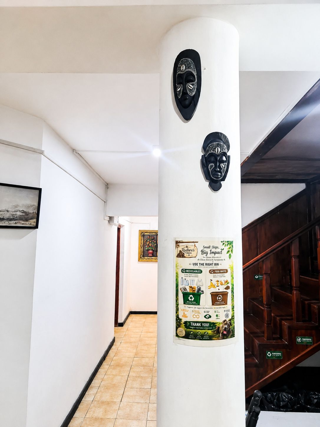A hallway with a white pillar featuring a recycling bin poster and two masks.