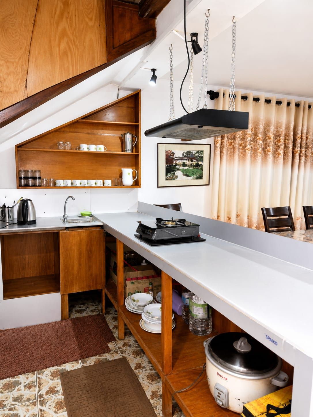 Una cocina compacta con armarios de madera, una encimera y una lámpara colgante.