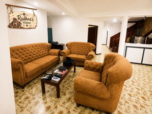 A living room with two brown sofas, a coffee table, and a sign reading 'Rudhra's Home'.