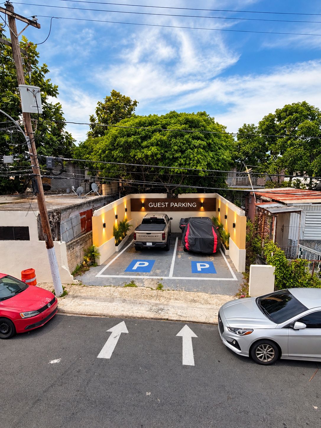 A guest parking area with two marked parking spaces, a Chevrolet pickup truck, and a covered vehicle.