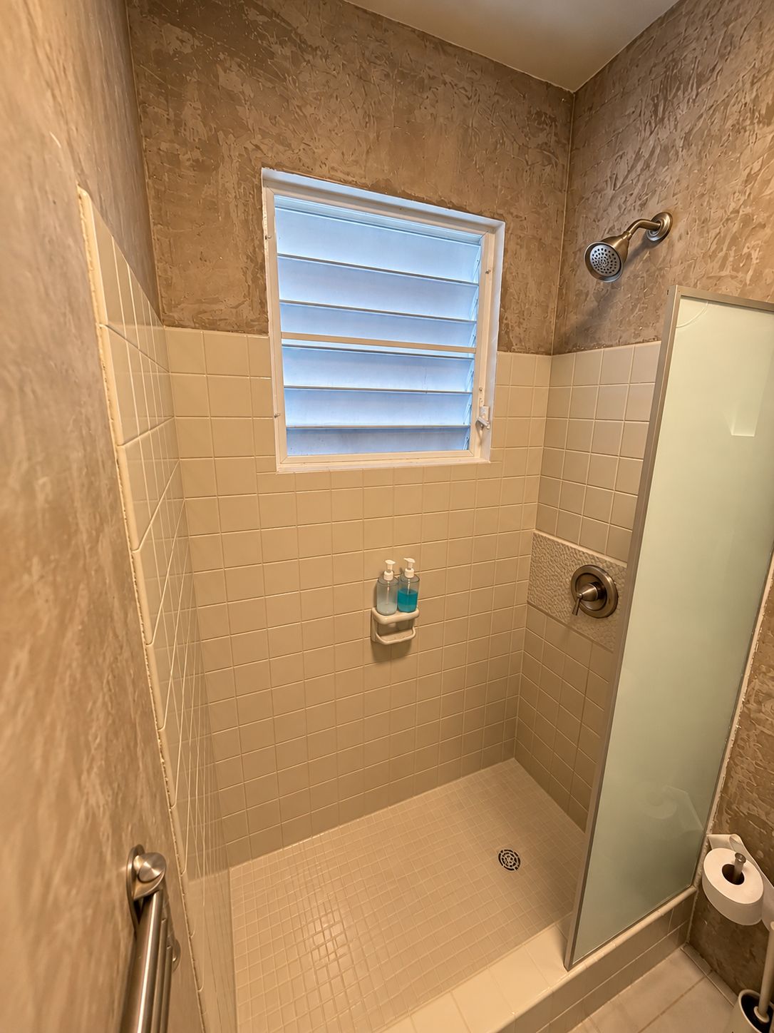 Un baño pequeño con ducha, ventana e inodoro.