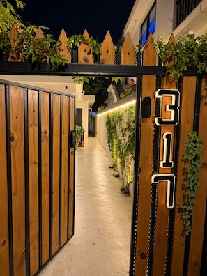 A gated entrance with a number sign, wooden panels, and a pathway leading to a building.