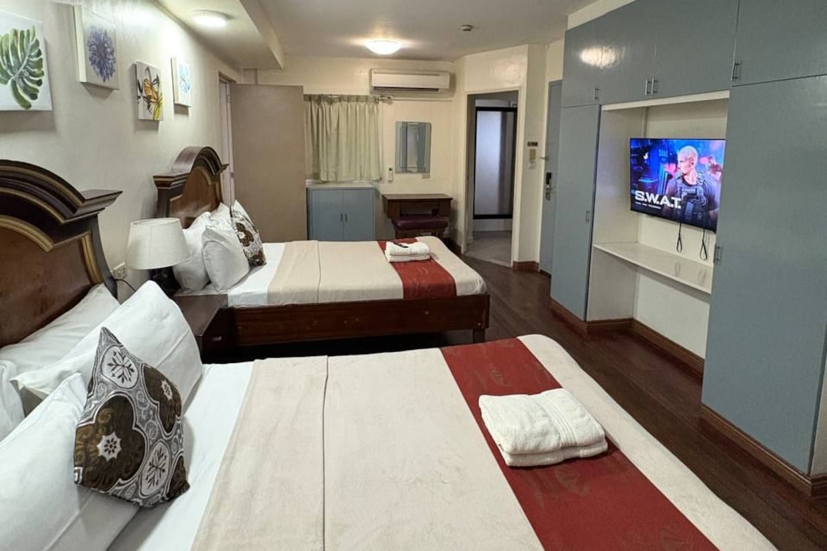 A hotel room with two beds, a television, and a wardrobe.