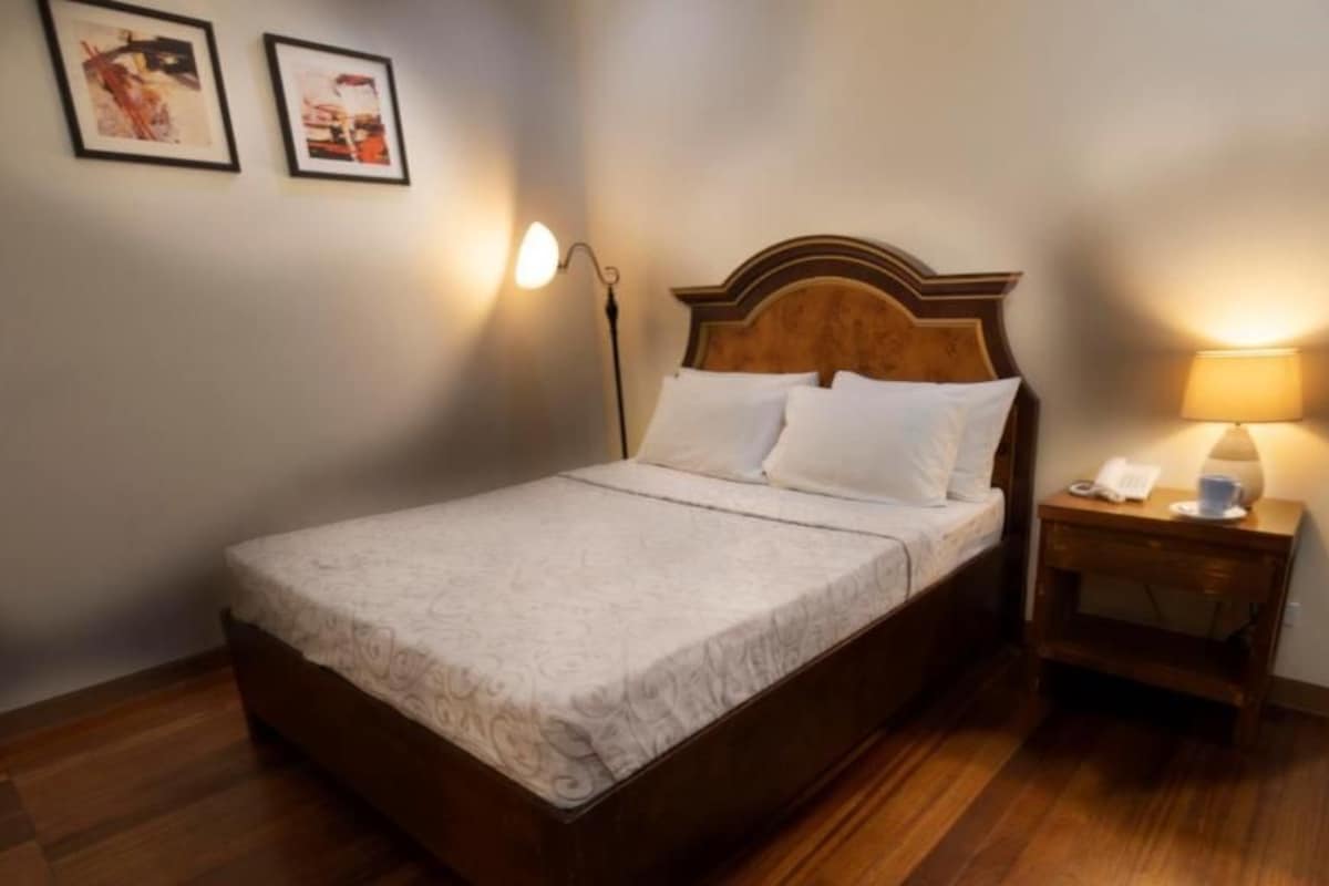 Une chambre d’hôtel avec un lit, une table de chevet, une lampe et deux tableaux encadrés au mur.