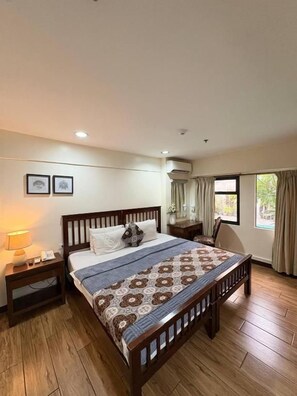 A bedroom with a wooden bed, bedside tables, a lamp, and a window with curtains. - 1775 Adriatico Suites (Manila)