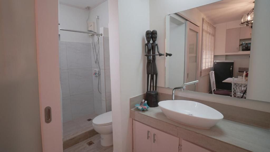 A bathroom with a shower, toilet, sink, and a mirror.