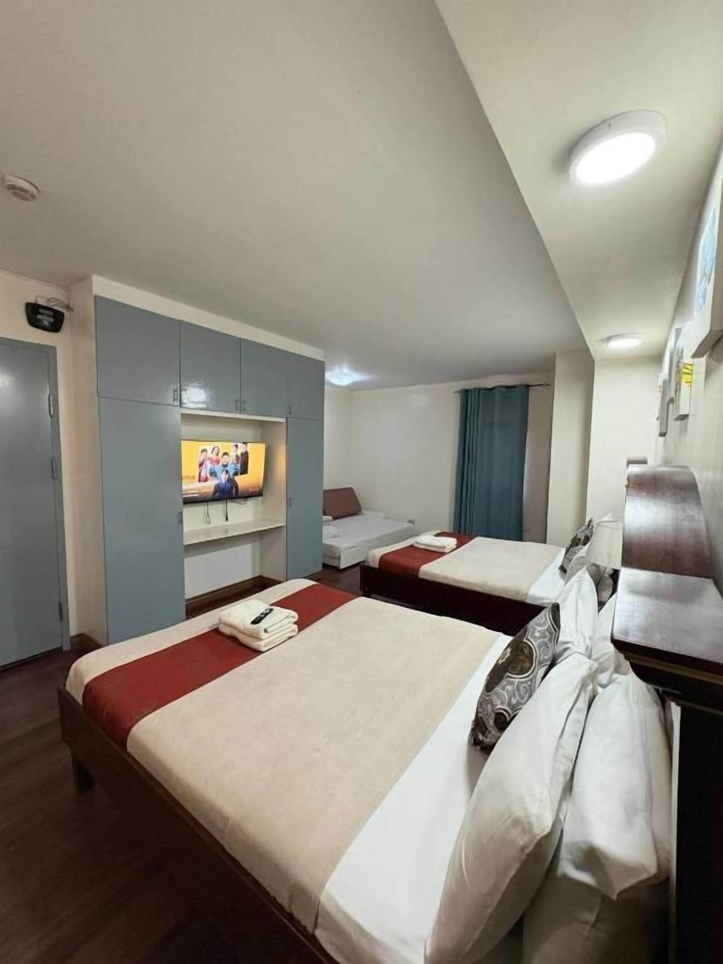 A hotel room with two beds, a TV, and a desk with a chair.