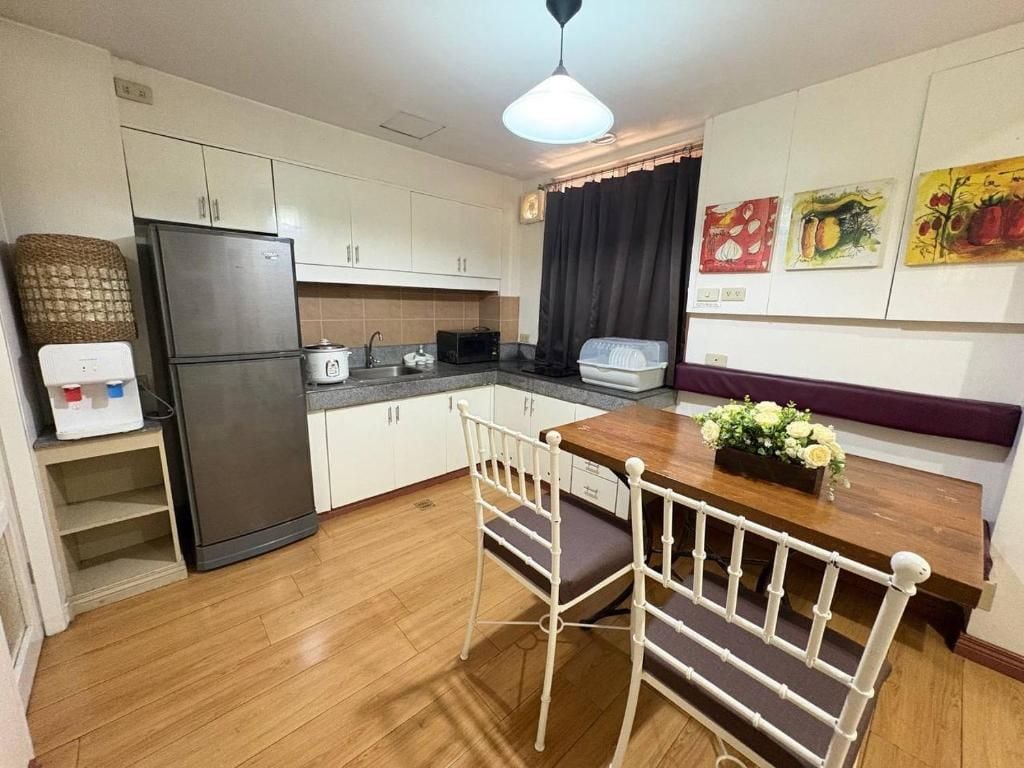 A compact kitchen with a refrigerator, stove, and dining table with chairs.