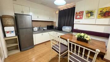 A compact kitchen with a refrigerator, stove, and dining table with chairs.