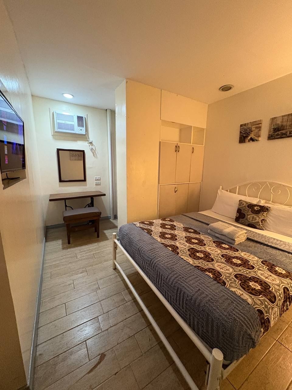 A bedroom with a bed, bedside table, and a desk with a chair.