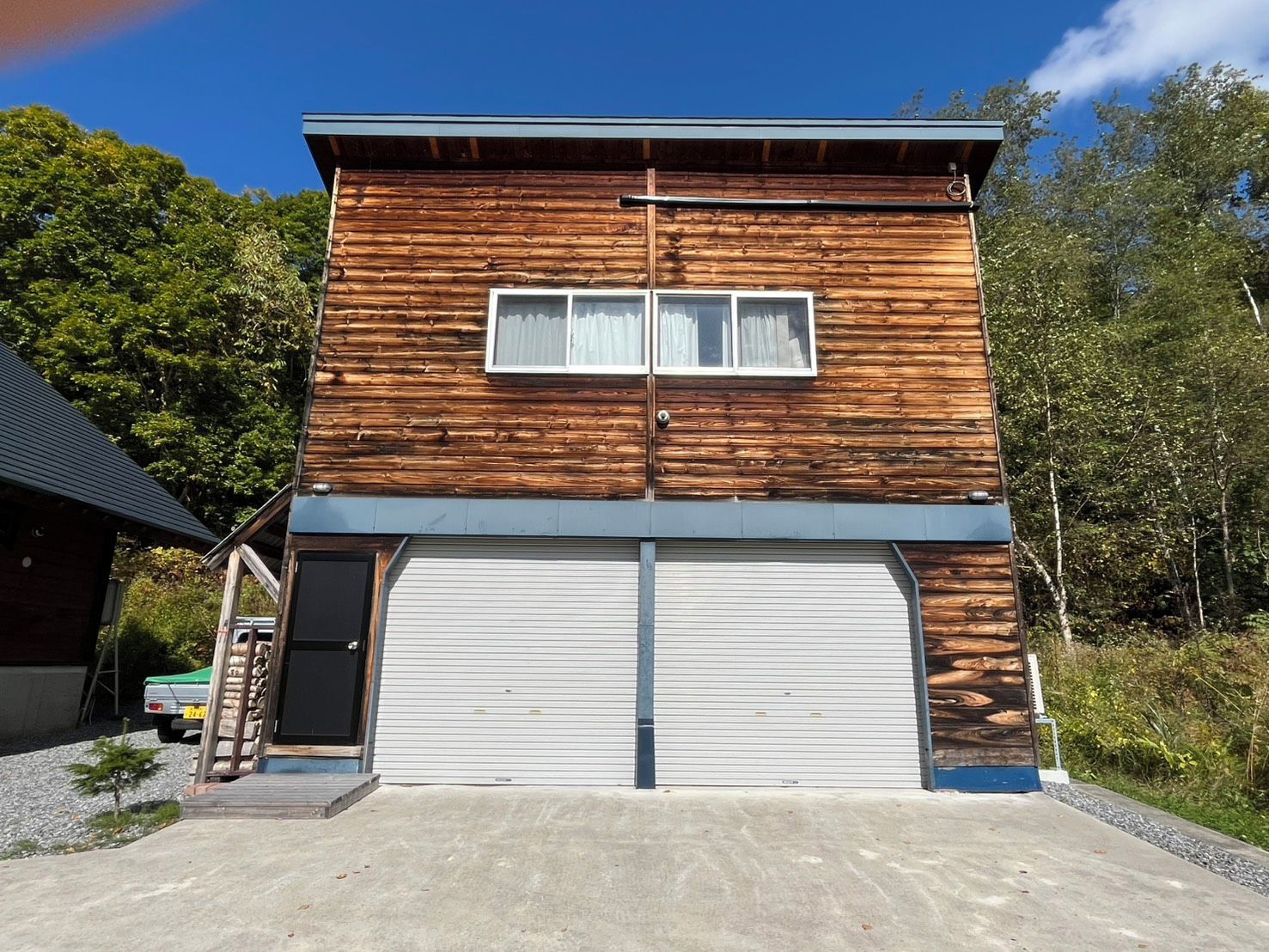 Un bâtiment à deux étages doté d’une porte de garage et d’un petit porche.