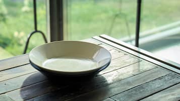 A bowl on a wooden table with a view of greenery through a window.