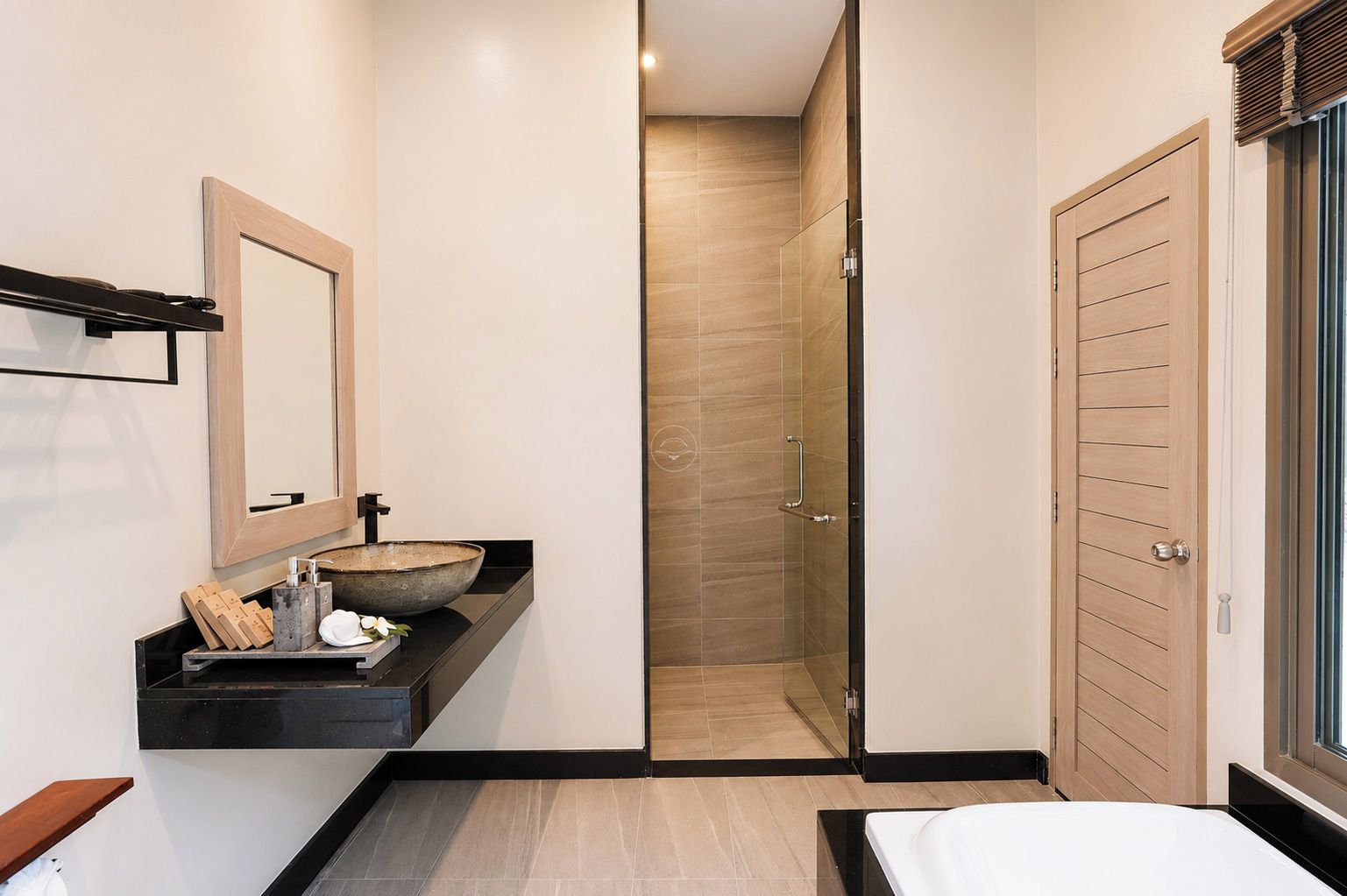 A modern bathroom with a large mirror, a vessel sink, and a walk-in shower.
