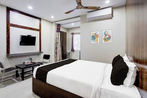 A hotel room with a bed, a desk, a chair, a television, an air conditioning unit, and artwork on the wall. - OYO Hotel O Renigunta Near Railway (Renigunta)