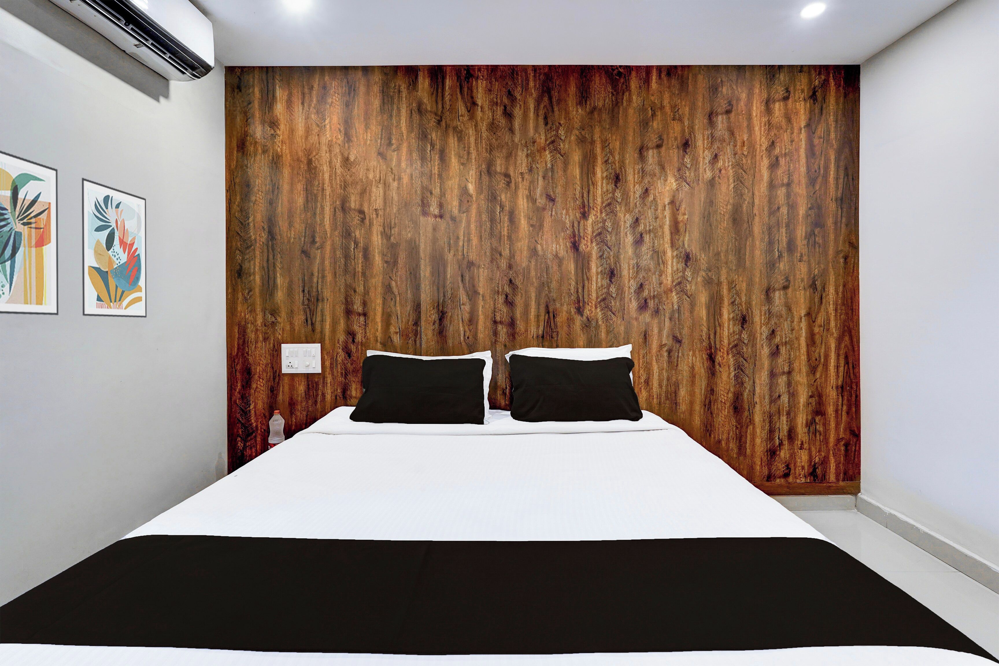 A bedroom with a wooden headboard, a bed with white bedding, and two black pillows.
