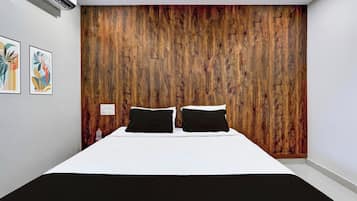 A bedroom with a wooden headboard, a bed with white bedding, and two black pillows.