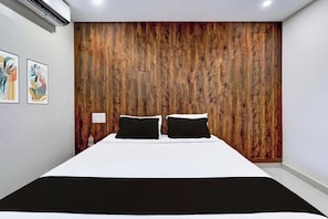 A bedroom with a wooden headboard, a bed with white bedding, and two black pillows.